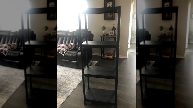 Aldi's black 4-tier utility shelf placed in a living room, photographed against the light