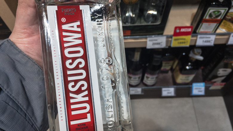 someone holding a bottle of luksusowa vodka