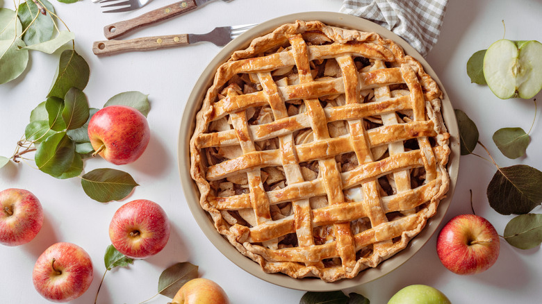 Overhead view of an apple pie surrounded by apples