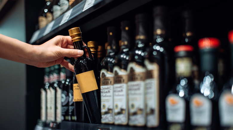 woman grabbing a bottle of vinegar off shelf