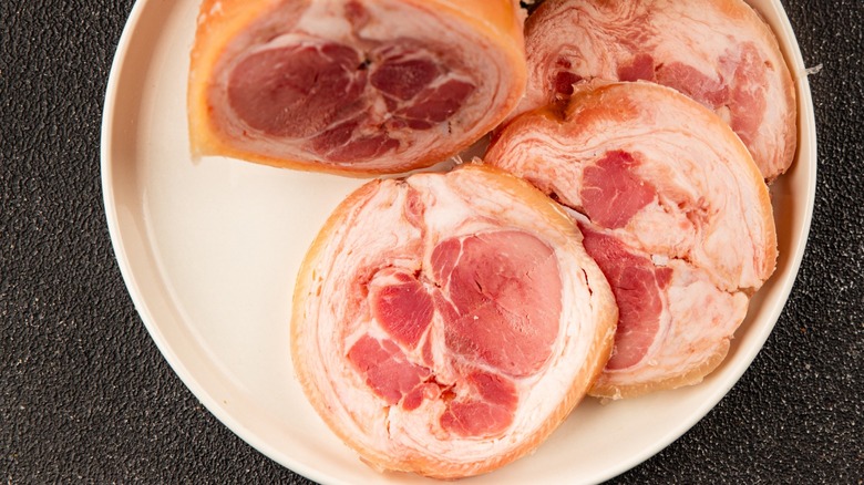fresh ham hock on steel tray with herbs