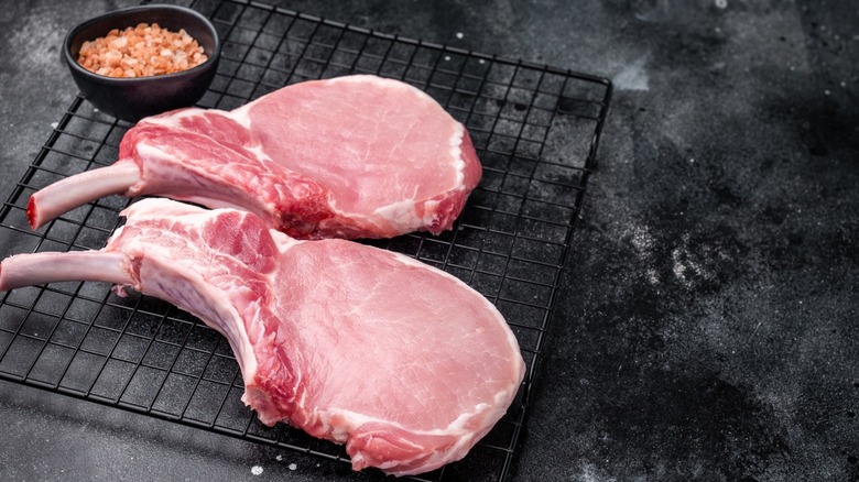 fresh pork chops on wired rack with pink salt