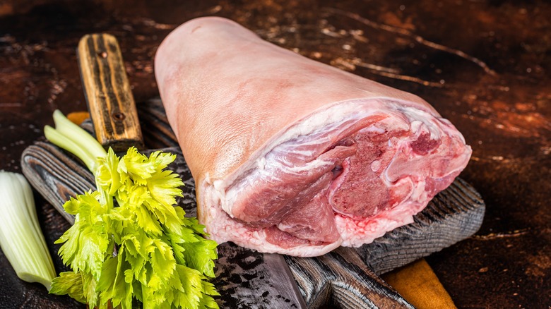 fresh pork shank of cutting board with celery