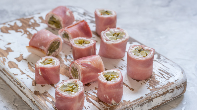A plate of ham roll-ups with cream cheese and pickles