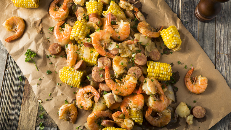 Traditional seafood boil with shrimp, potatoes, and corn on the cob spread over brown paper.