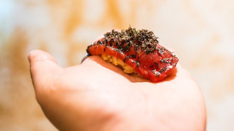 Hand holding akami over rice