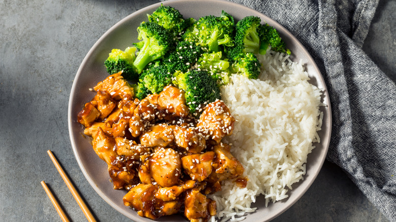 A bowl of chicken, broccoli, and rice is photographed from above.