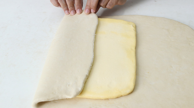 Hands laminating a sheet of dough