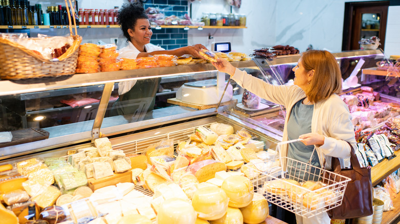 Person at deli counter handing another person a packaged cheese product