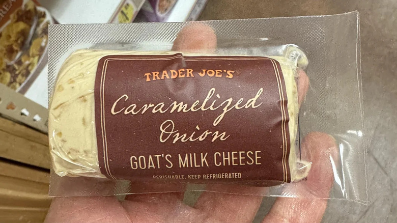 A hand holding a package of Caramelized Onion Goat's Milk Cheese