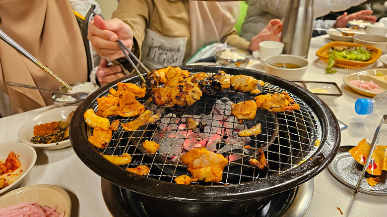 Grilling chicken thighs on a tabletop at a Korean restaurant