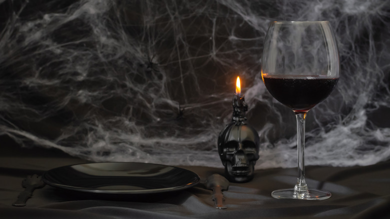 Glass of red wine and black candle and plate