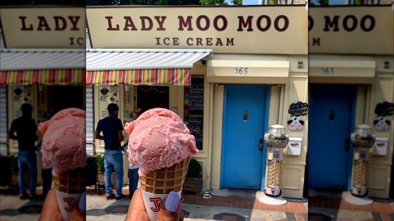 Person holding a pink ice cream cone in front of Lady Moo Moo's exterior