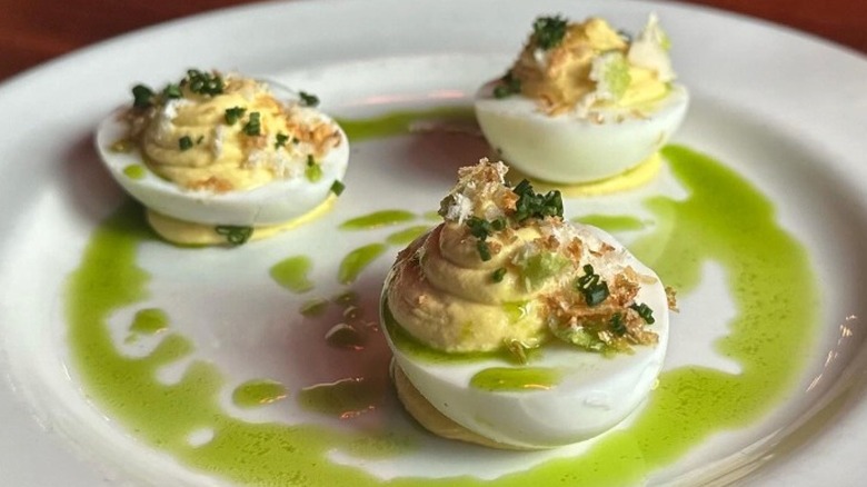 Three fancy deviled eggs on a plate with green sauce at Zig Zag Cafe in Seattle.