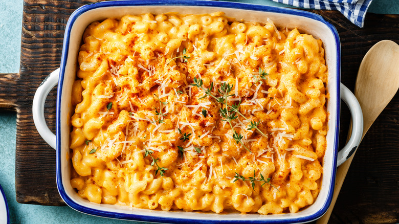 Creamy macaroni and cheese in white bowls next to metal spoons
