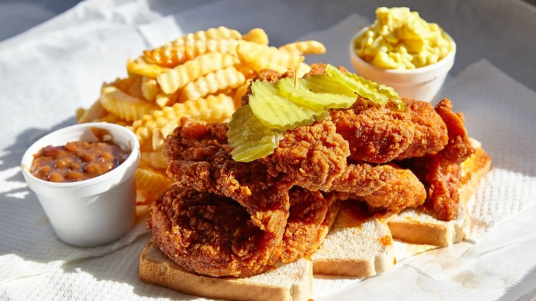 A plate of Prince's hot chicken with pickles, fries, and beans