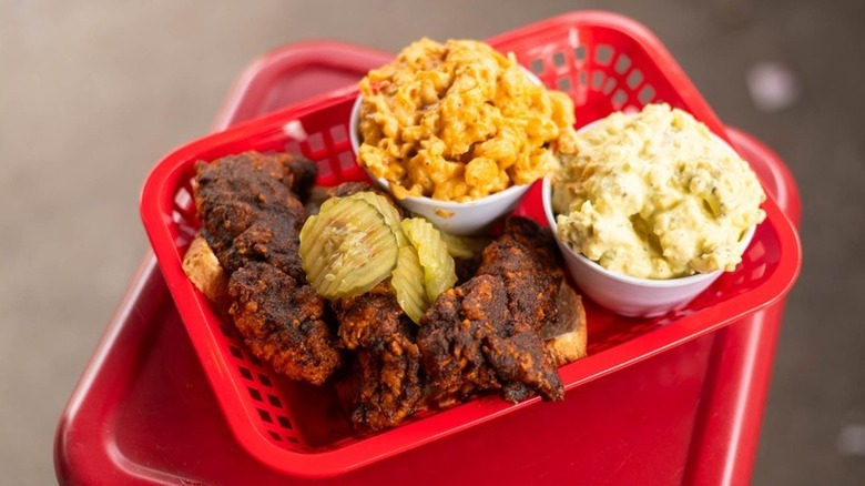 a red basket with fried chicken, mac and cheese, pickles, and mashed potatoes