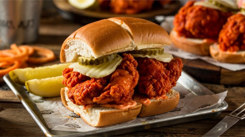 a Nashville hot chicken sandwich with pickles on a metal tray
