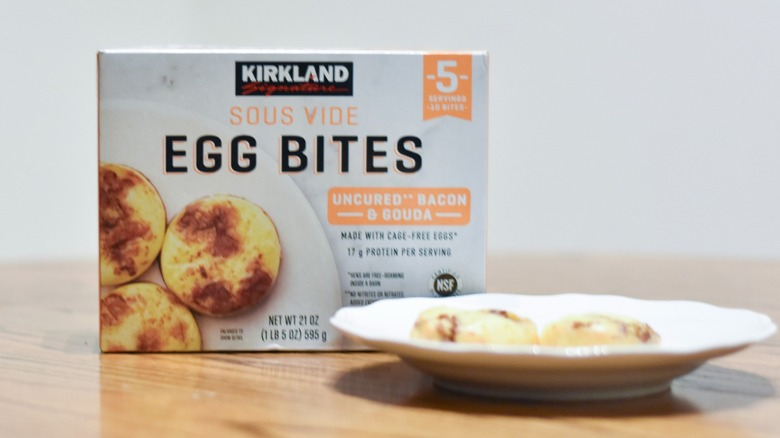A box of sous vide egg bites behind a white plate with two egg bites