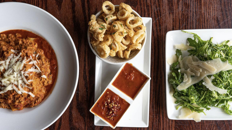 close-up of fried calamari and other Italian dishes on brown, wooden table