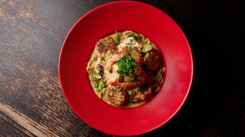 Italian food in red dish on brown, wooden table