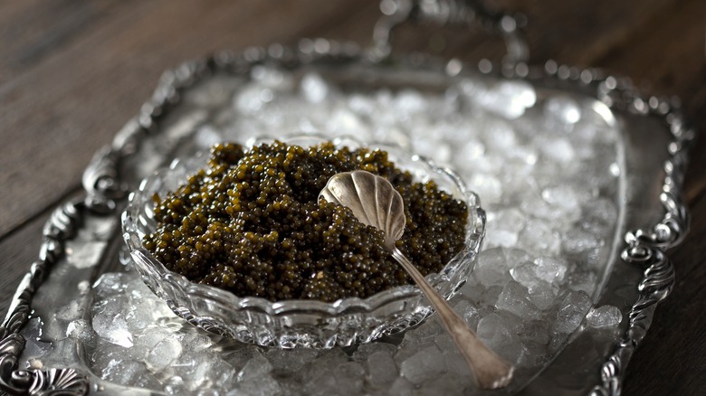 A crystal bowl of caviar rests on a tray of ice