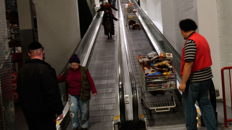 Escalator in Brooklyn Costco being used by customers and an employee
