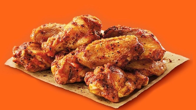 Little Caesars Wings sitting on paper with orange-red background