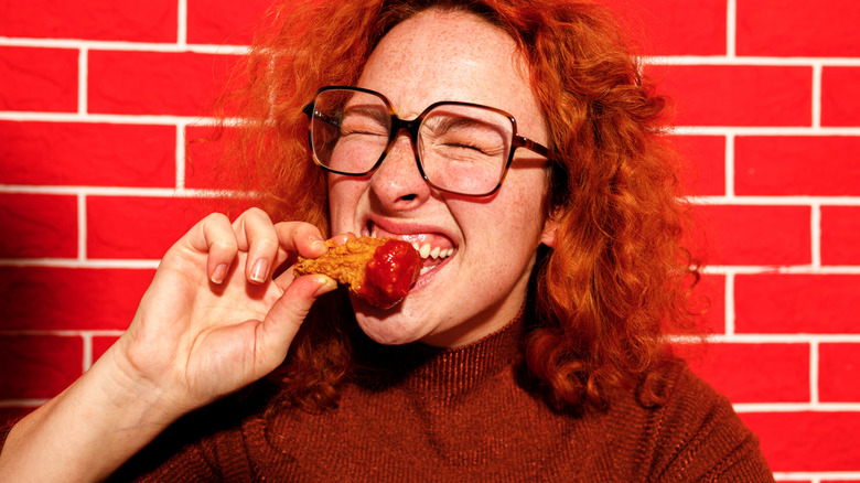 Woman makes a face while eating wings