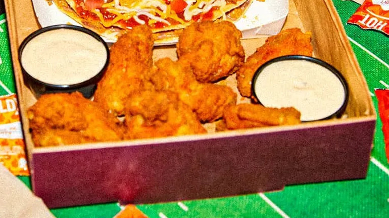 Taco Bell Wings on one side of a box with two dipping sauces