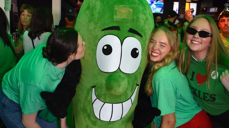 Three woman post with a person in a pickle costume