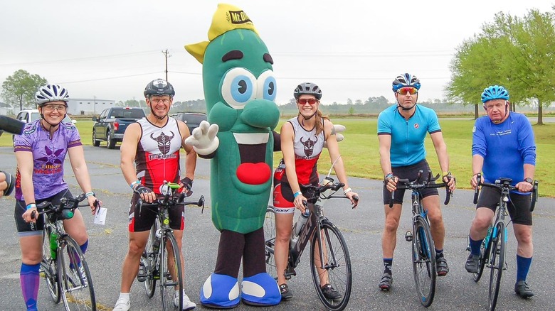 People on bikes pose with a person in a pickle costume