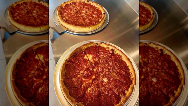 Two whole deep dish pizzas on trays