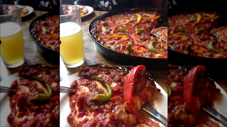 Slice of deep dish pizza with green and red peppers on a white plate with a cold beer