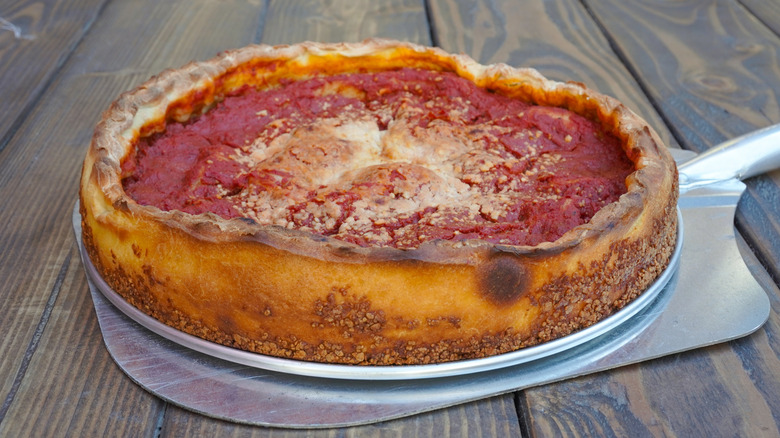 Whole deep dish pizza fresh out of the oven on a wooden table