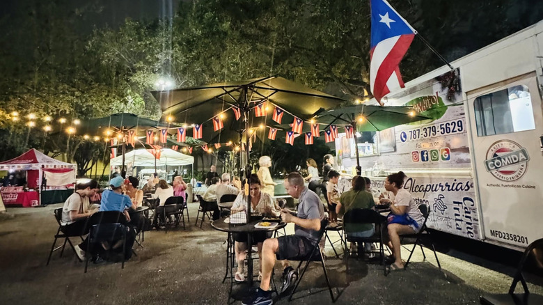 People eating outside the Ay Bendito Con Sabor a Puerto Rico food truck.