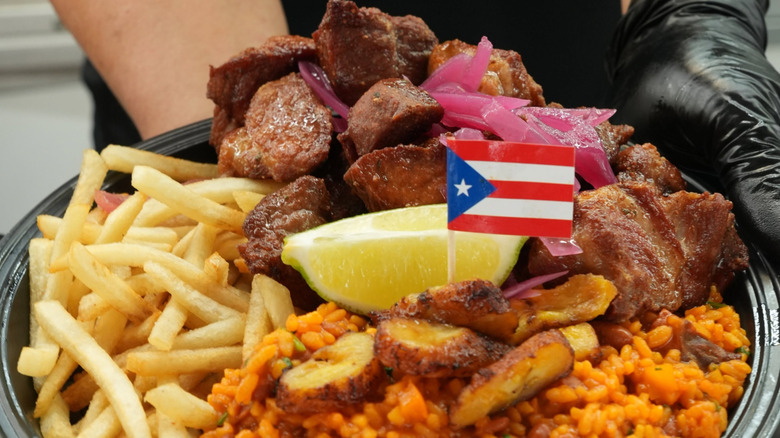 Person serving a meal with a flag in it from El Sazon de Puerto Rico.
