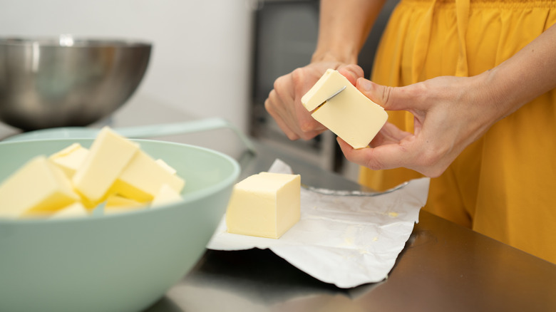 Woman cutting butter next to a bowl