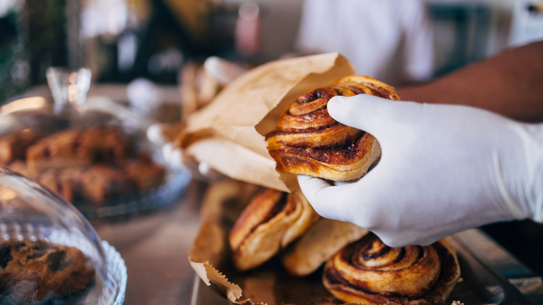 Person placing cinnamon roll in bag