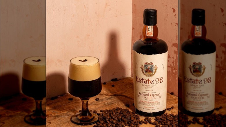 Estate 98 espresso liqueur with martini on wooden table in corner with coffee beans scattered around them