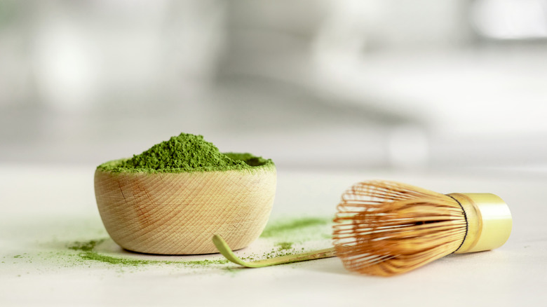 Matcha powder in a wooden bowl with bamboo whisk