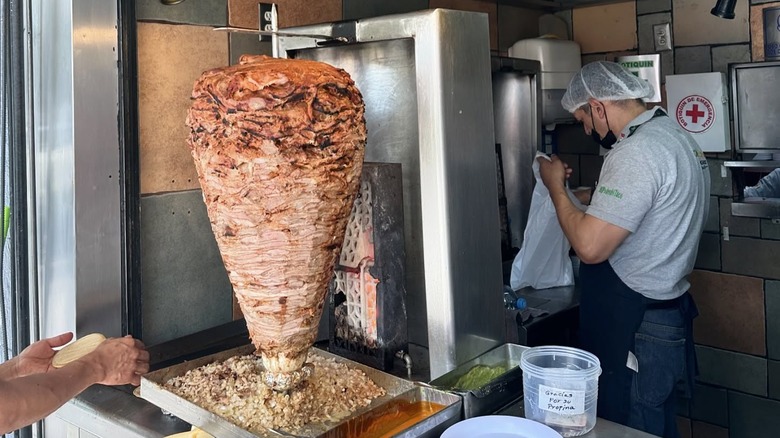 Worker standing by the spit at El Huequito.