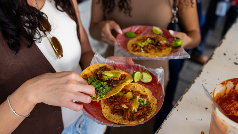Two women eating tacos el pastor in Mexico City.