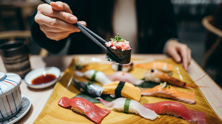 A diner using chopsticks at a sushi restaurant