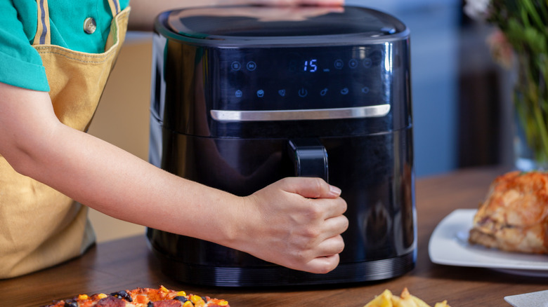 Someone holding the handle of an air fryer