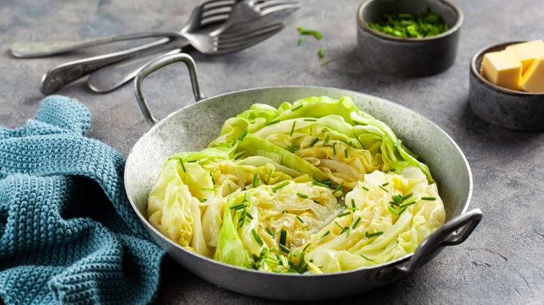 Steamed cabbage in a bowl with forks and toppings