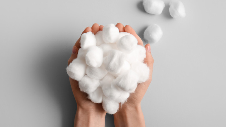 hands holding cotton balls on gray background