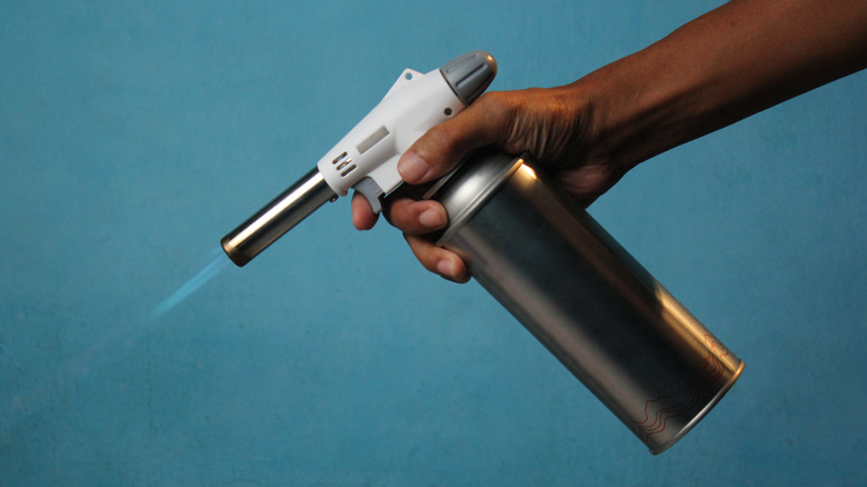 hand holding portable butane torch