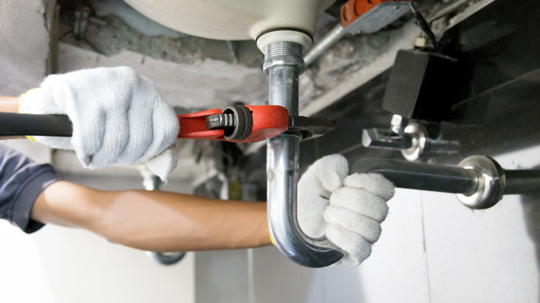person fixing a potential leak under the sink