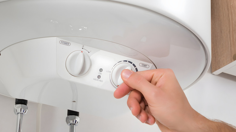 man's hand running a water heater system check